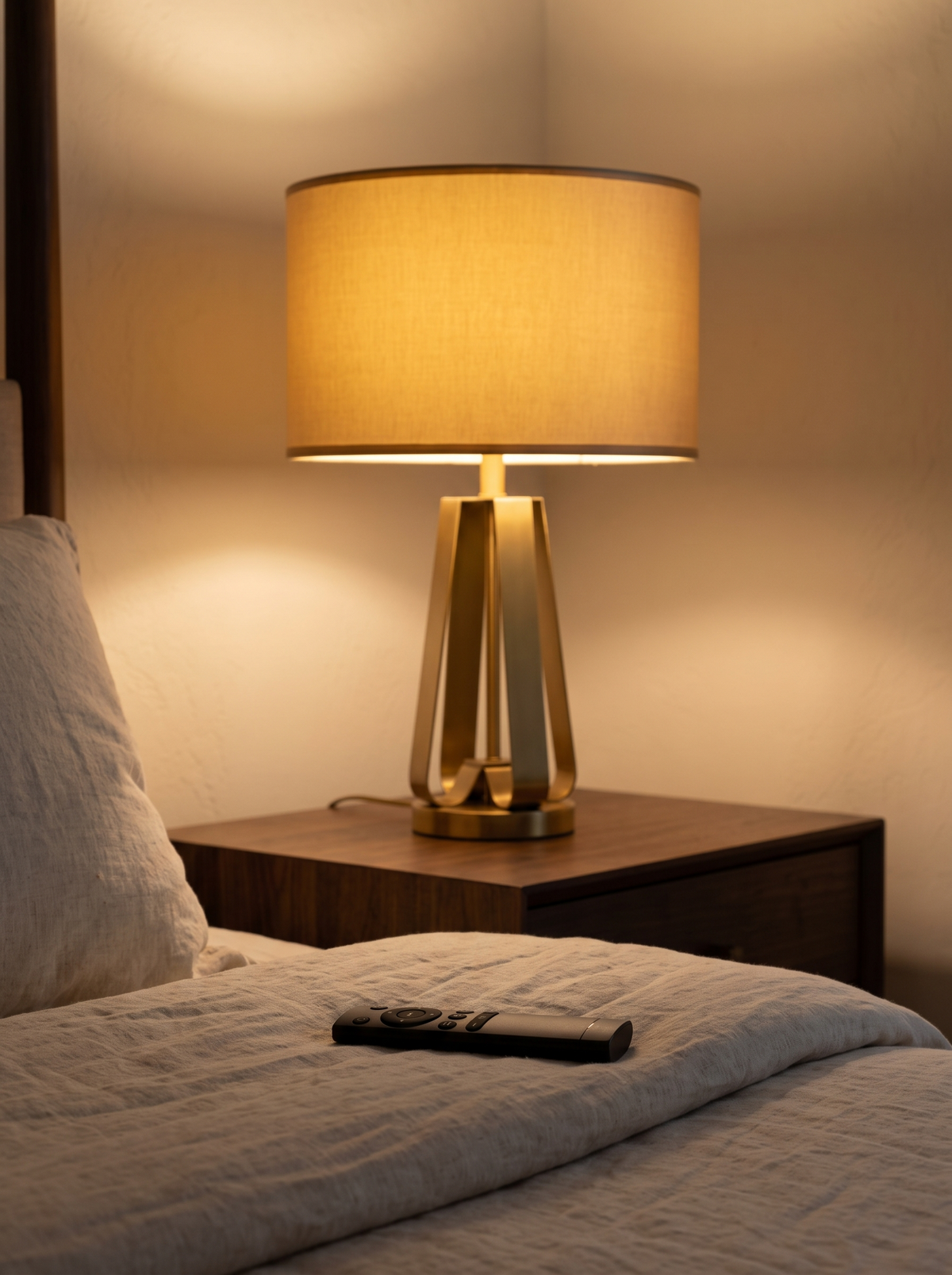 Solstice lamp lit beside a bed with the remote in reach